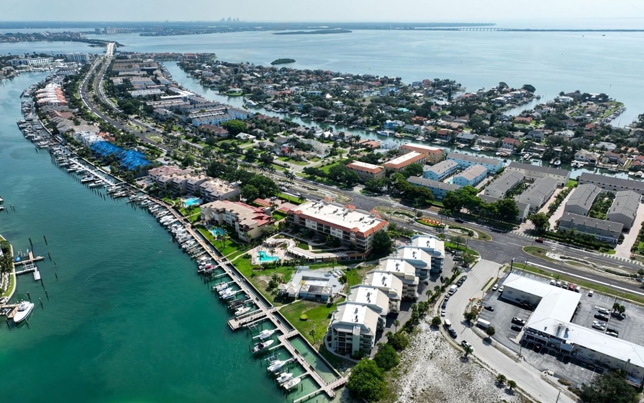 An aerial view of Tierra Verde, Florida, shows a long, narrow island dotted with numerous residential buildings and a winding road.