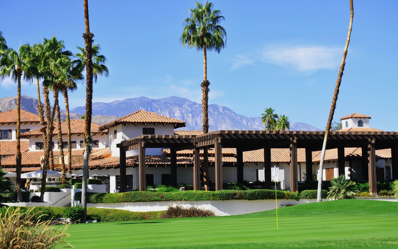 Bluestone homes beside a manicured golf course, with palms and mountains behind them.