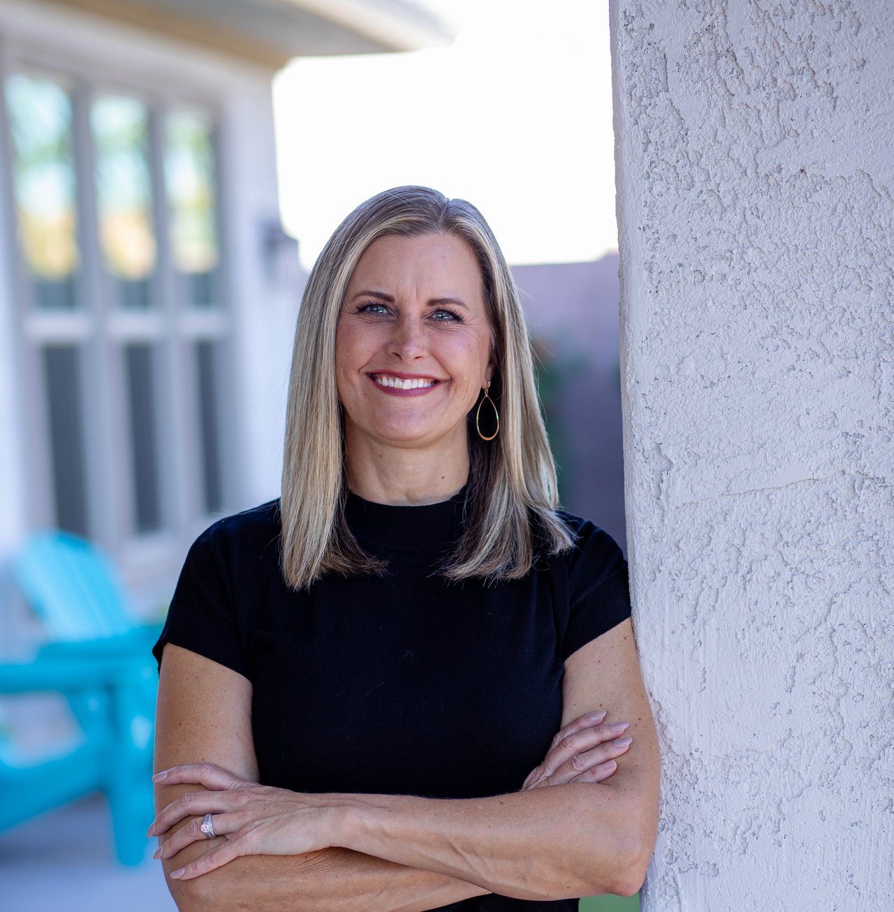 Amber Smale smiling with her arms crossed beside a stucco wall.