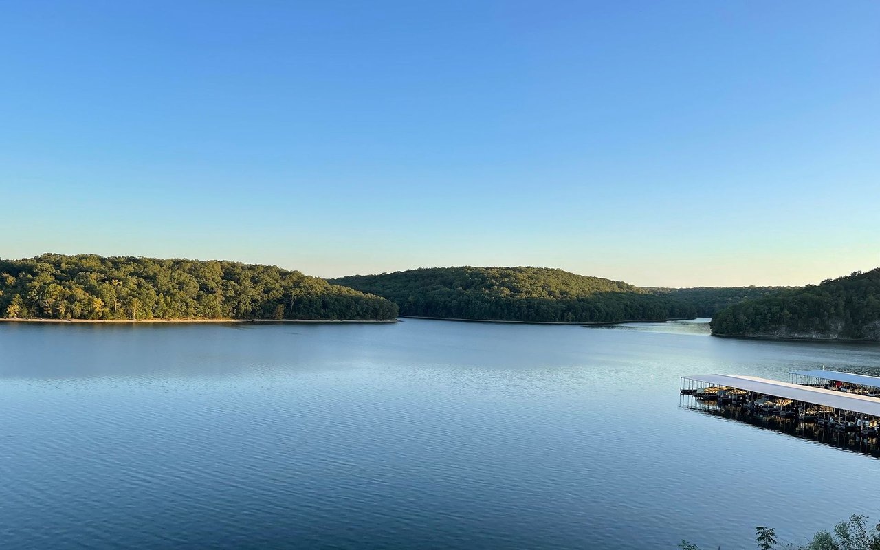 Lake of the Ozarks with wooded hills, calm water, and covered boat docks.