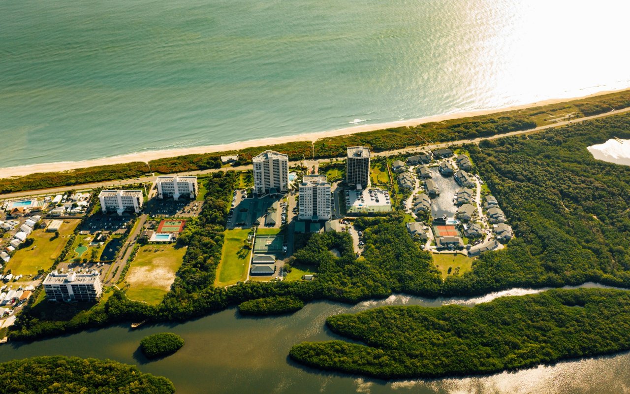 Coastal buildings and homes sit between a sandy beach and winding waterways.