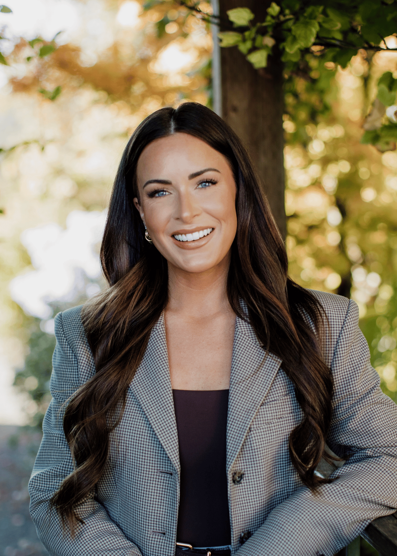 Megan Moore smiling outdoors in a gray checked blazer.