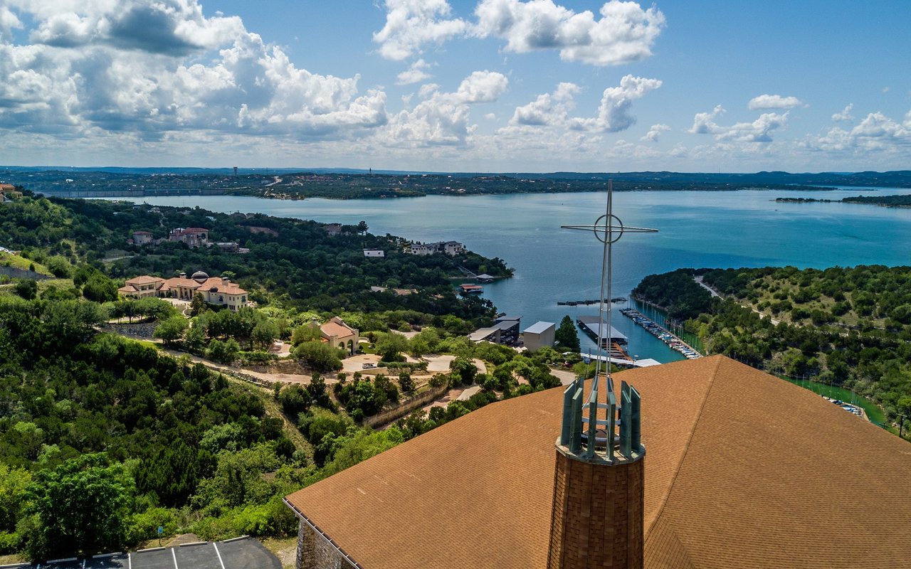 Panoramic view of Lakeway and Lake Travis, with hillside homes, a marina, and a church roof.