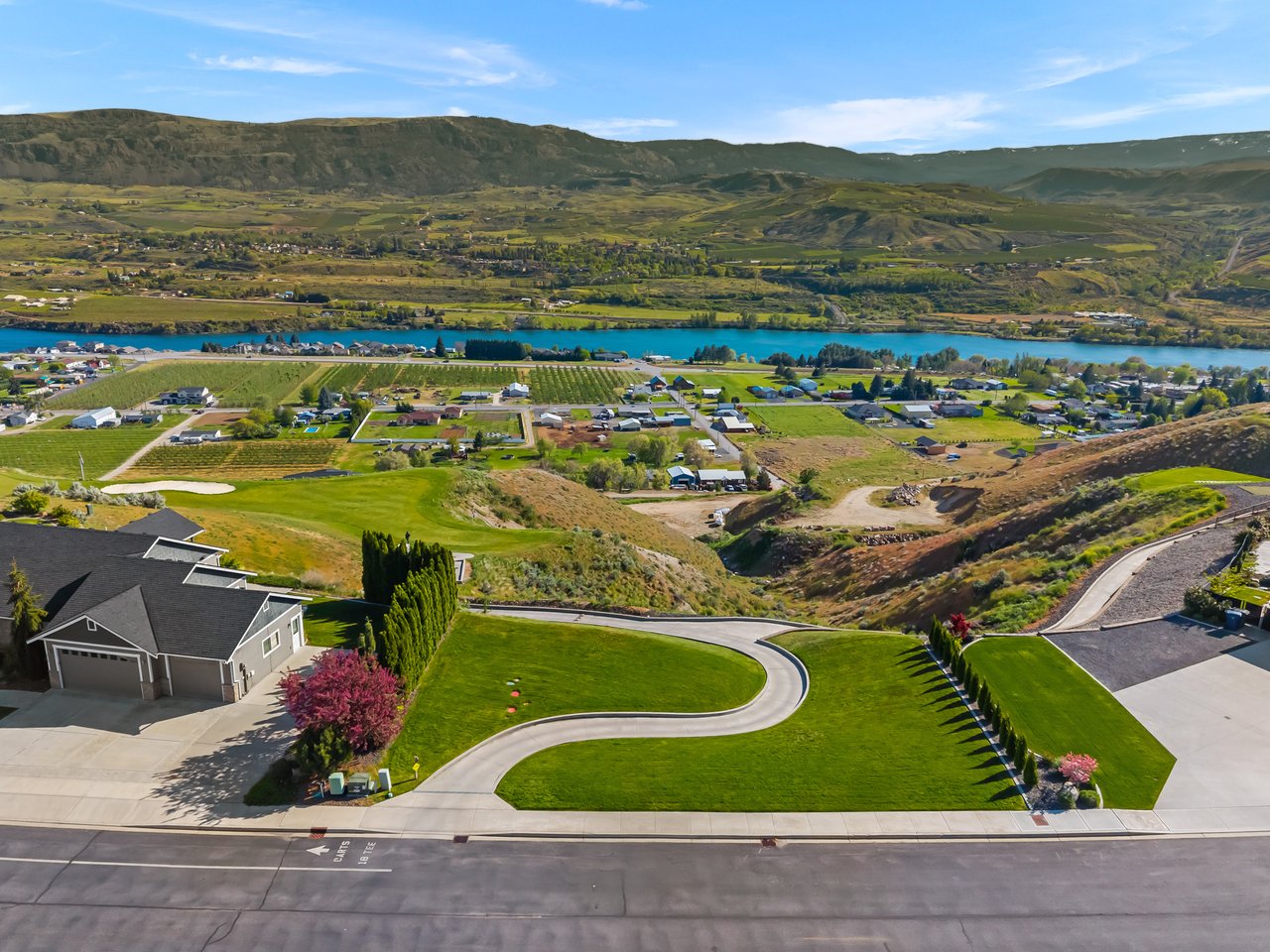 Aerial view of Crescent Bar homes and fields beside a blue river and rolling hills.
