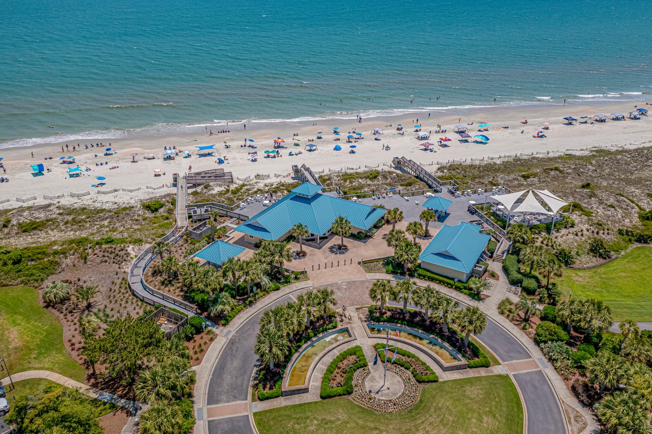 Beach and coastal pavilion complex with turquoise roofs, boardwalks, and landscaped grounds.