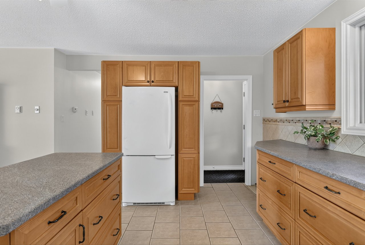 Kitchen with honey-colored cabinets, gray countertops, and a white refrigerator.