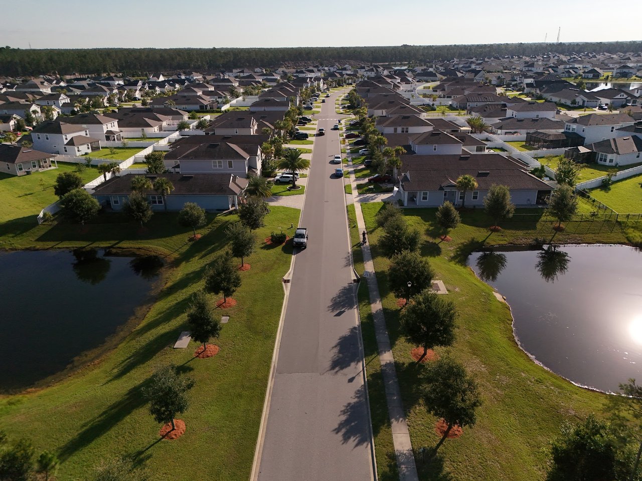 Aerial view of homes along a neighborhood street, with landscaped yards and ponds.