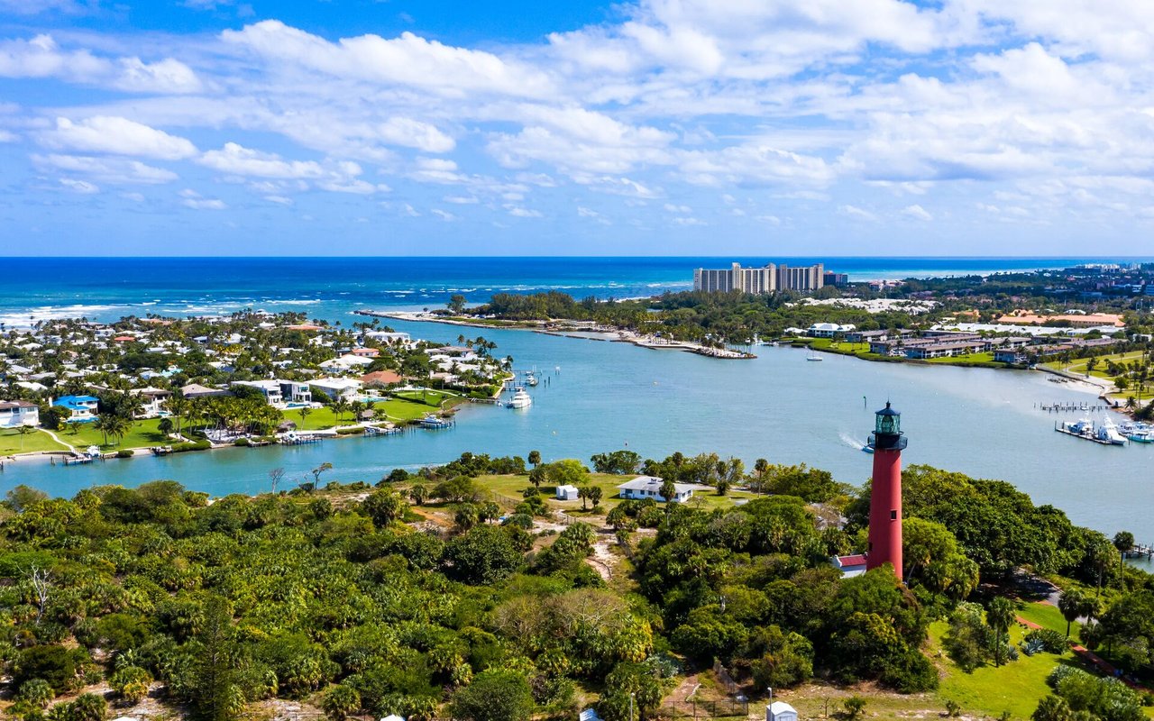 Aerial view of Jupiter Inlet with the red lighthouse, waterways, coastline, and ocean.