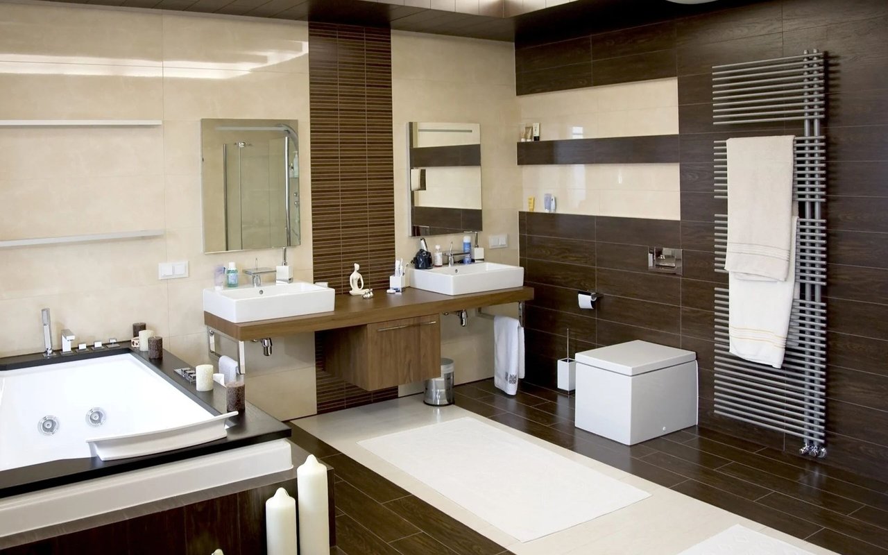 Modern bathroom with a jetted tub, double sinks, dark tile, and a towel warmer.