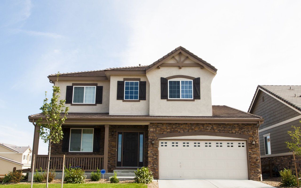 Two-story house with a stone facade, covered porch, and attached two-car garage.