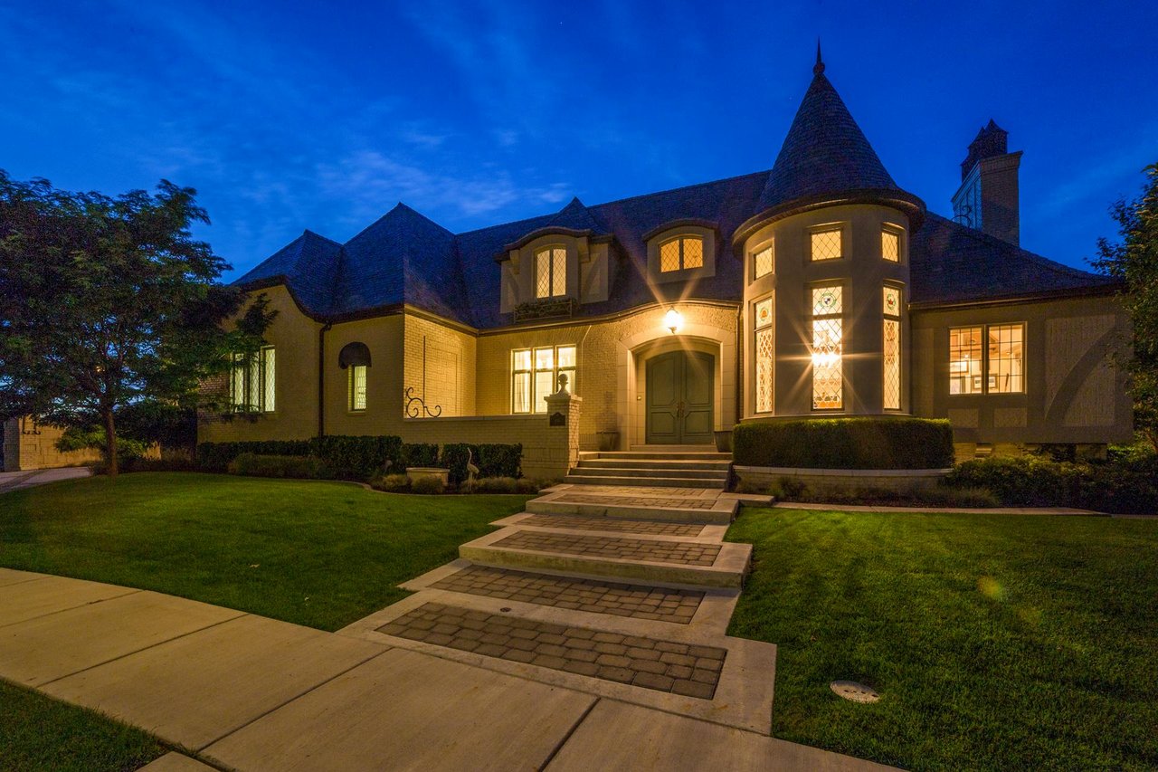 Elegant luxury estate home with classic architecture, manicured lawn, and warm exterior lighting at dusk