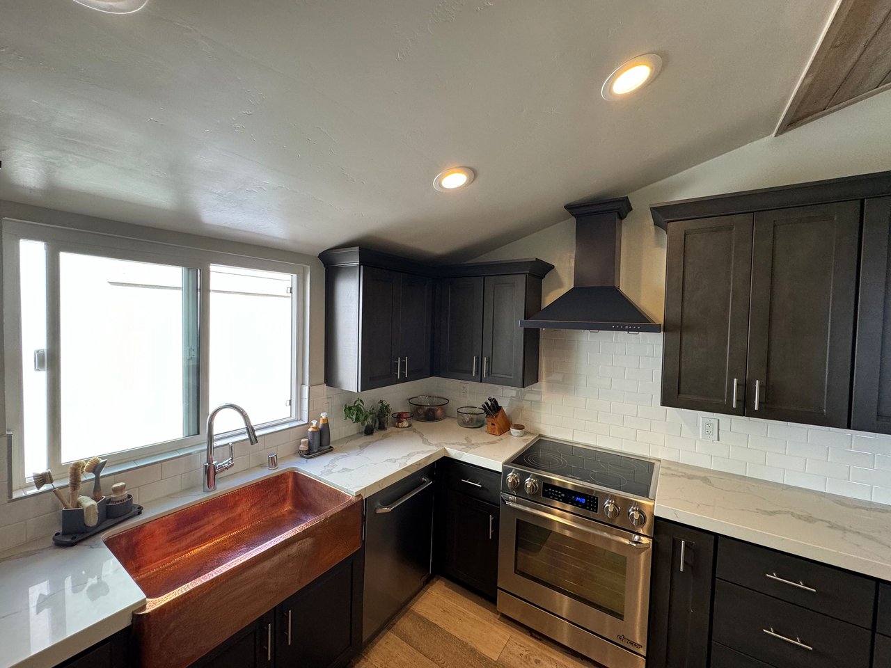 Modern kitchen featuring a copper farmhouse sink, stainless steel oven, dark cabinetry, and quartz countertops at 533 S Sierra Ave, Solana Beach, CA 92075 oceanview rental.