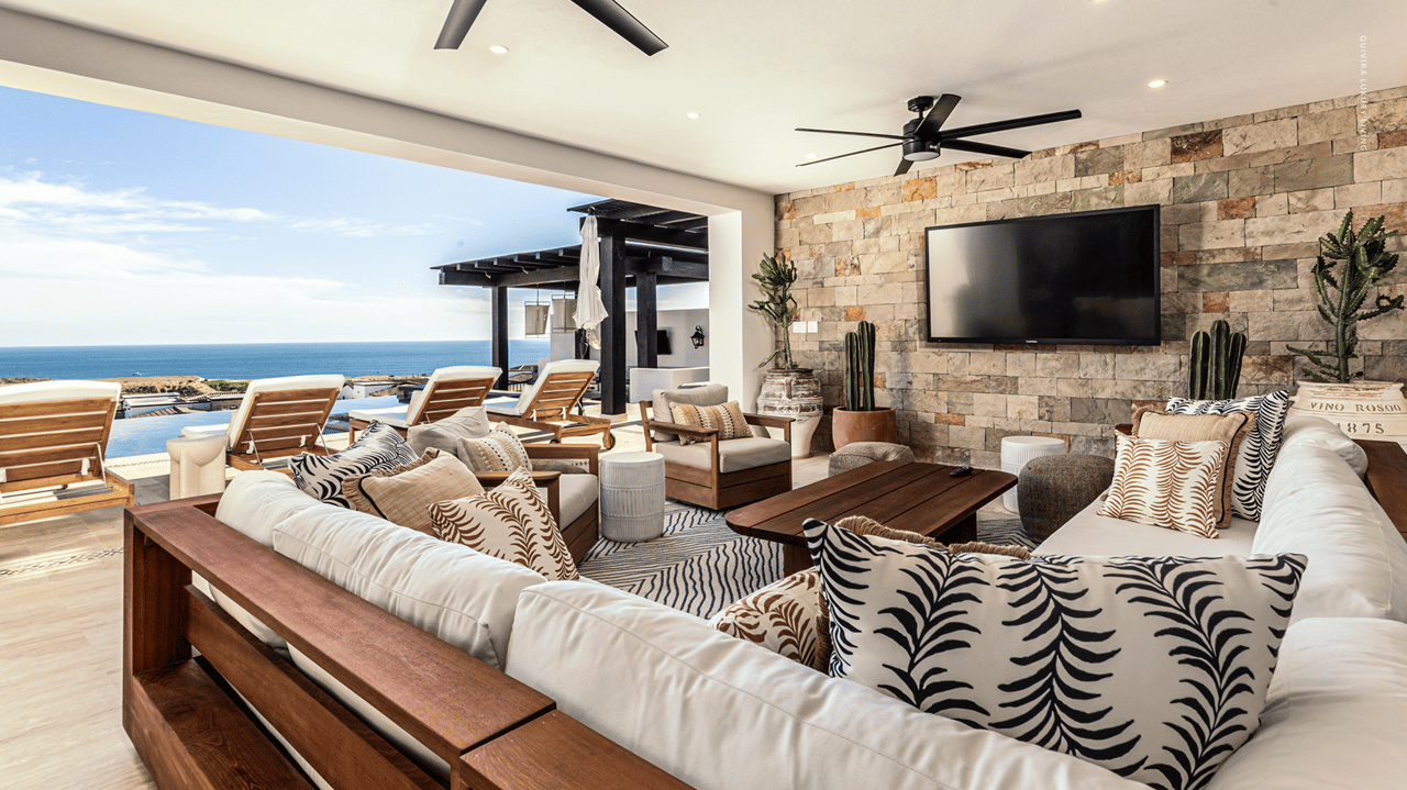 Living room with white sofas and a stone wall opening onto an ocean-view terrace.