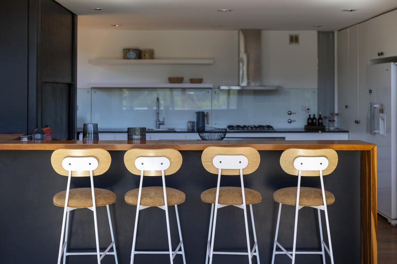 Modern kitchen with a wood-topped island and four white-and-wood bar stools.