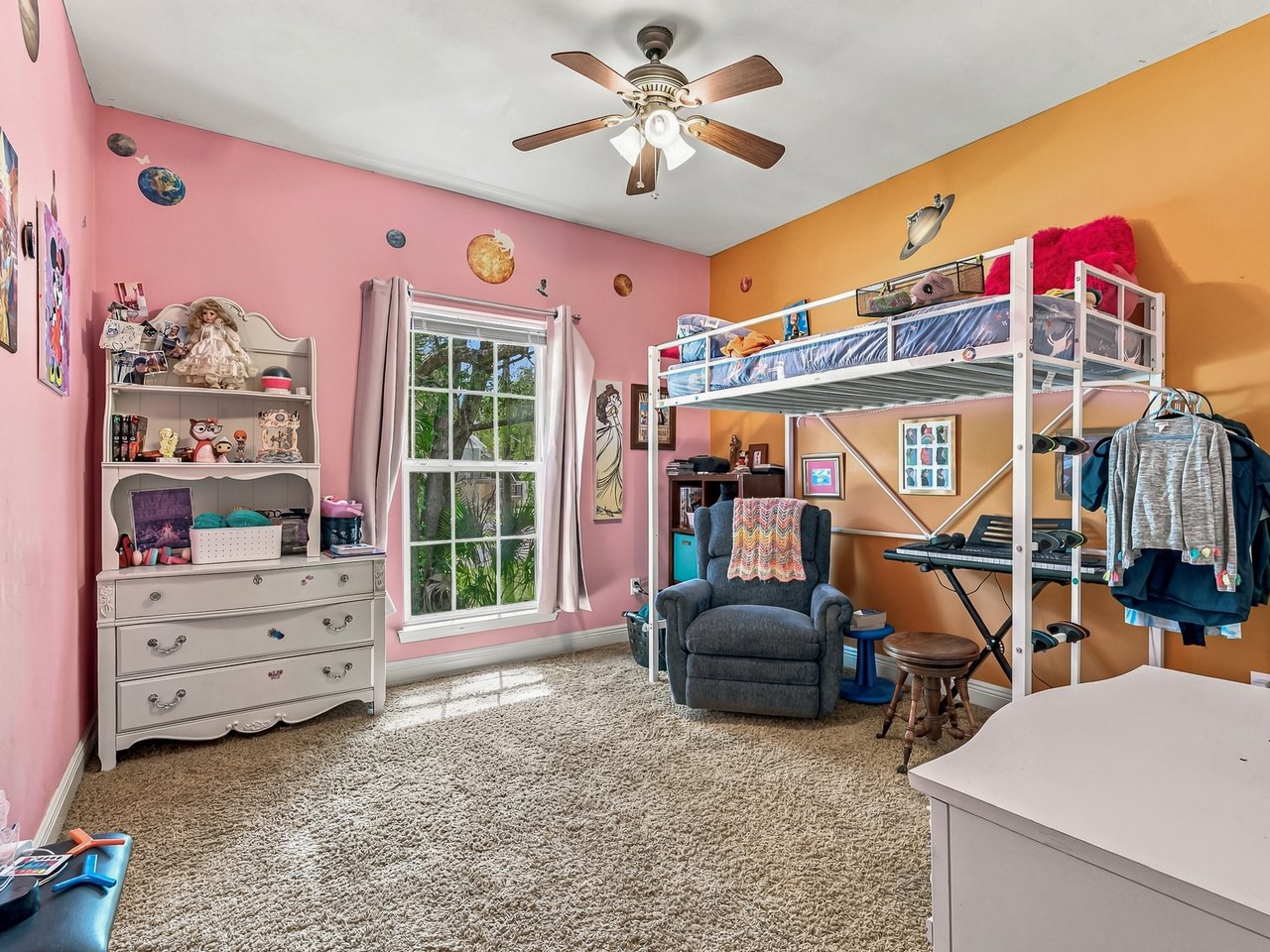 Colorful bedroom with a loft bunk bed, toy shelves, and a sunlit window.