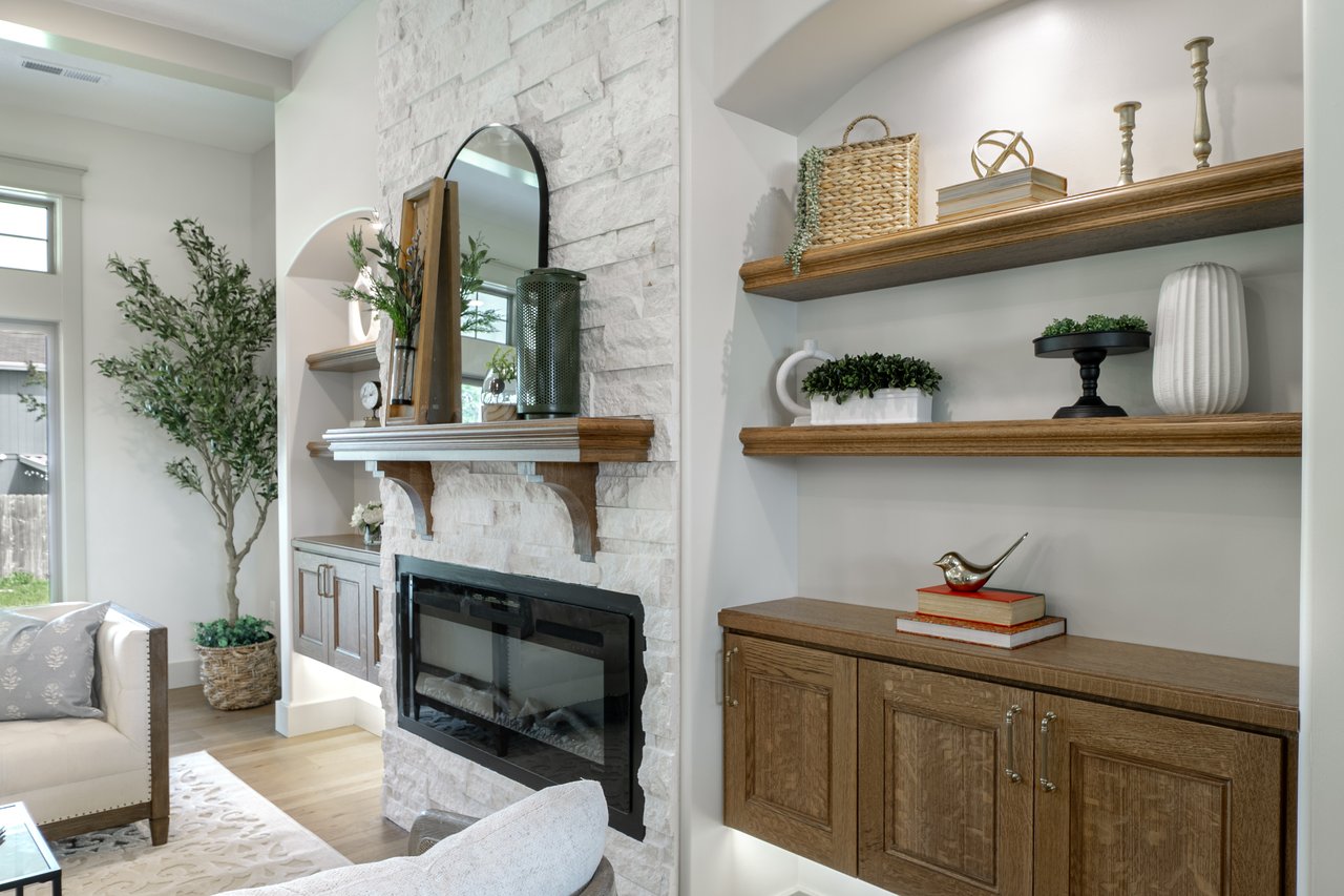 Living room with a white stone fireplace and built-in wooden shelves and cabinetry.
