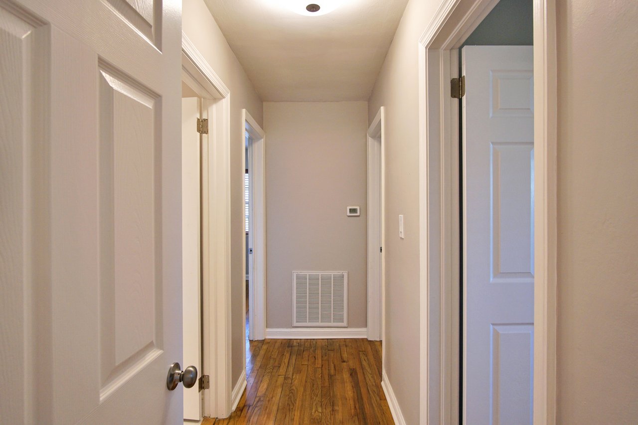 A well-lit hallway featuring a door and an elegant light fixture overhead.