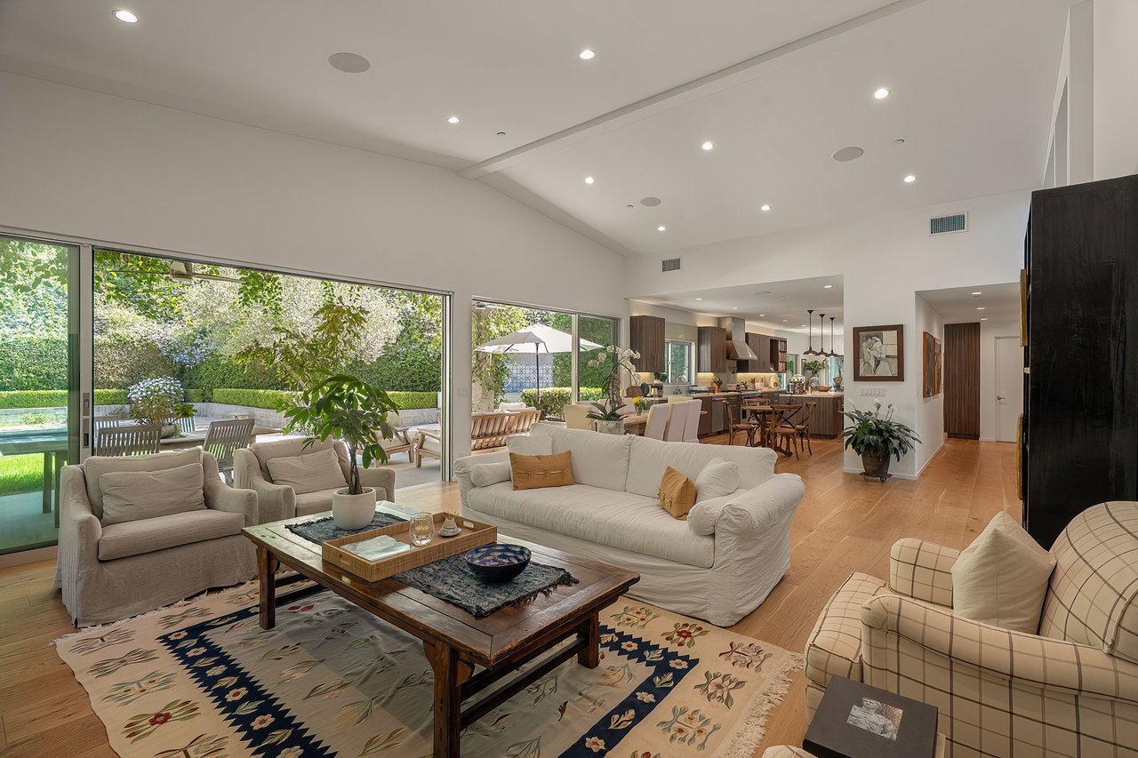 Open-plan living room with vaulted ceiling and wide glass doors overlooking a patio and pool.