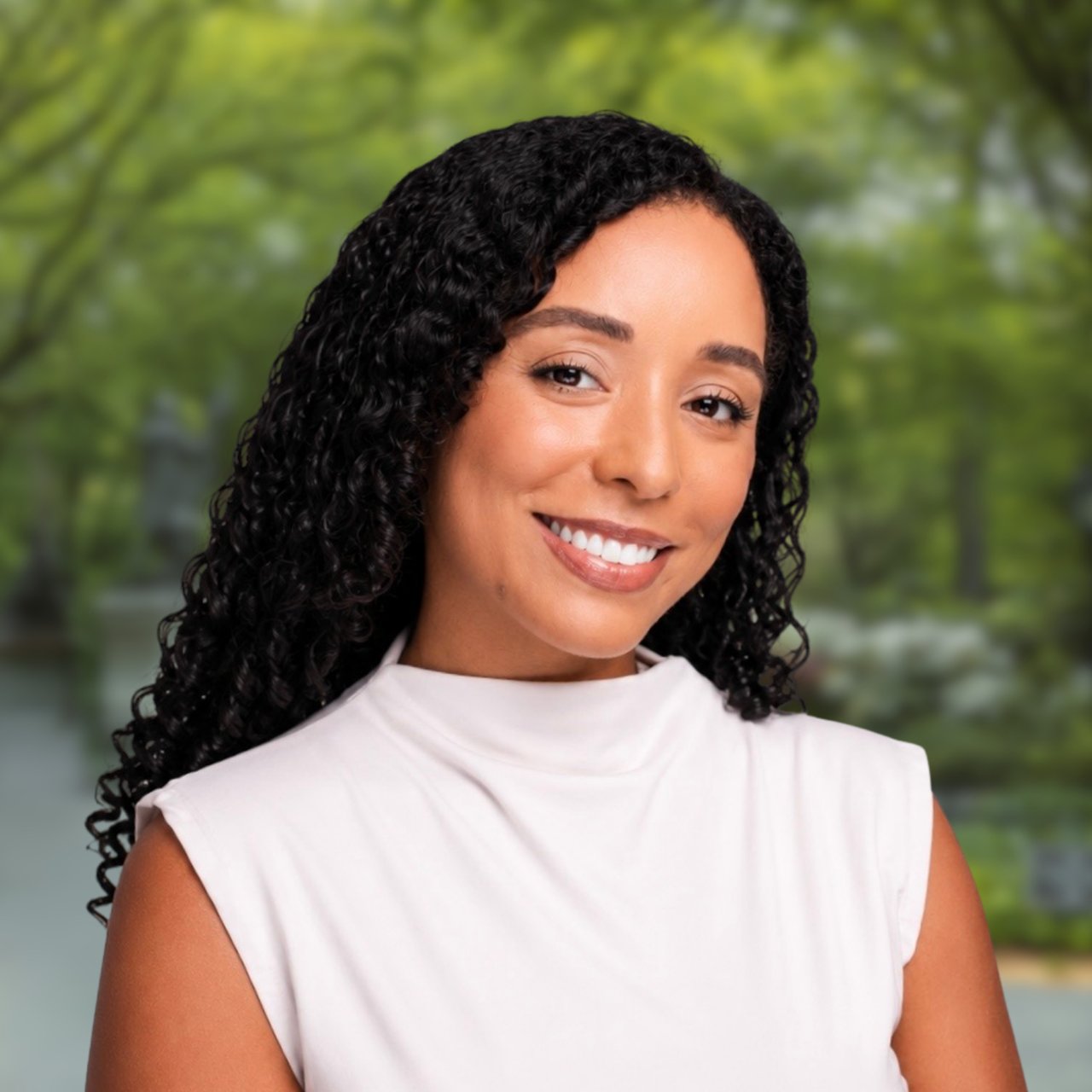 Lidier Carela smiling in a white sleeveless top against a blurred green background.