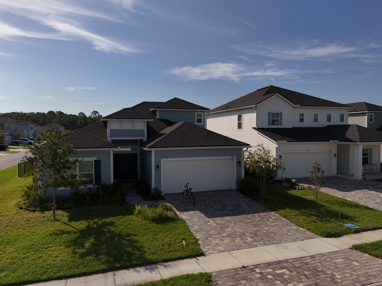 Modern suburban homes with attached garages, paved driveways, and front lawns.
