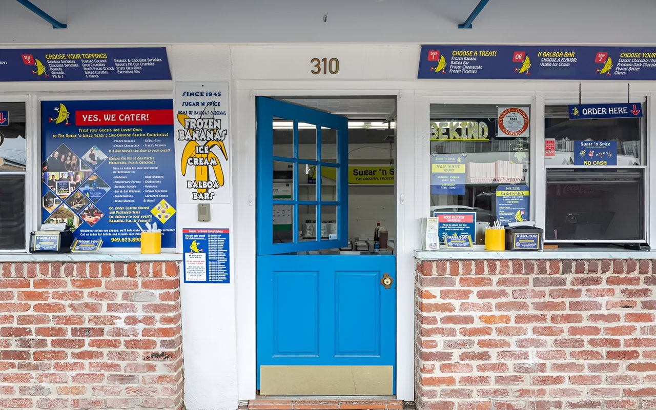  The entrance of the "Sugar 'n Spice" ice cream shop, featuring a half-open blue Dutch door and a red brick exterior.