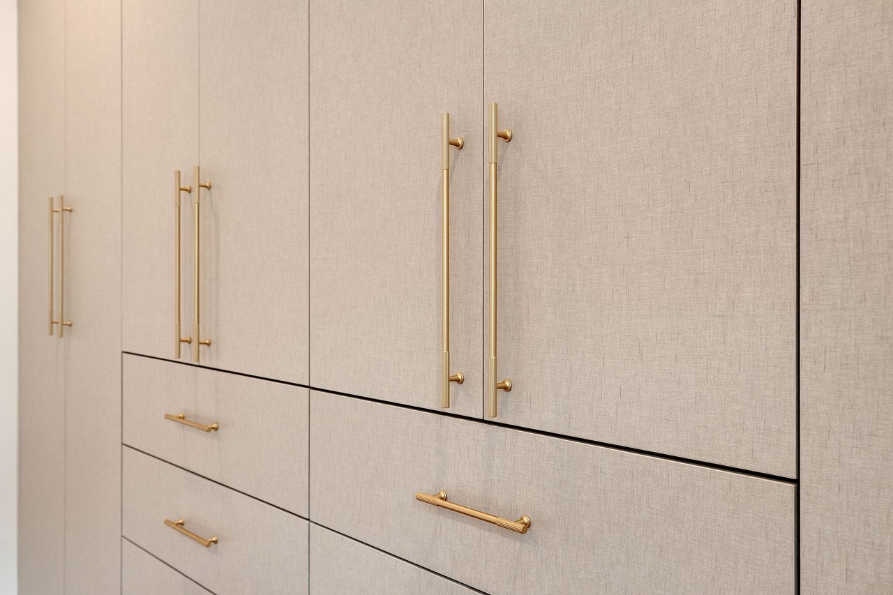 Beige built-in cabinetry with textured fronts and long gold handles.