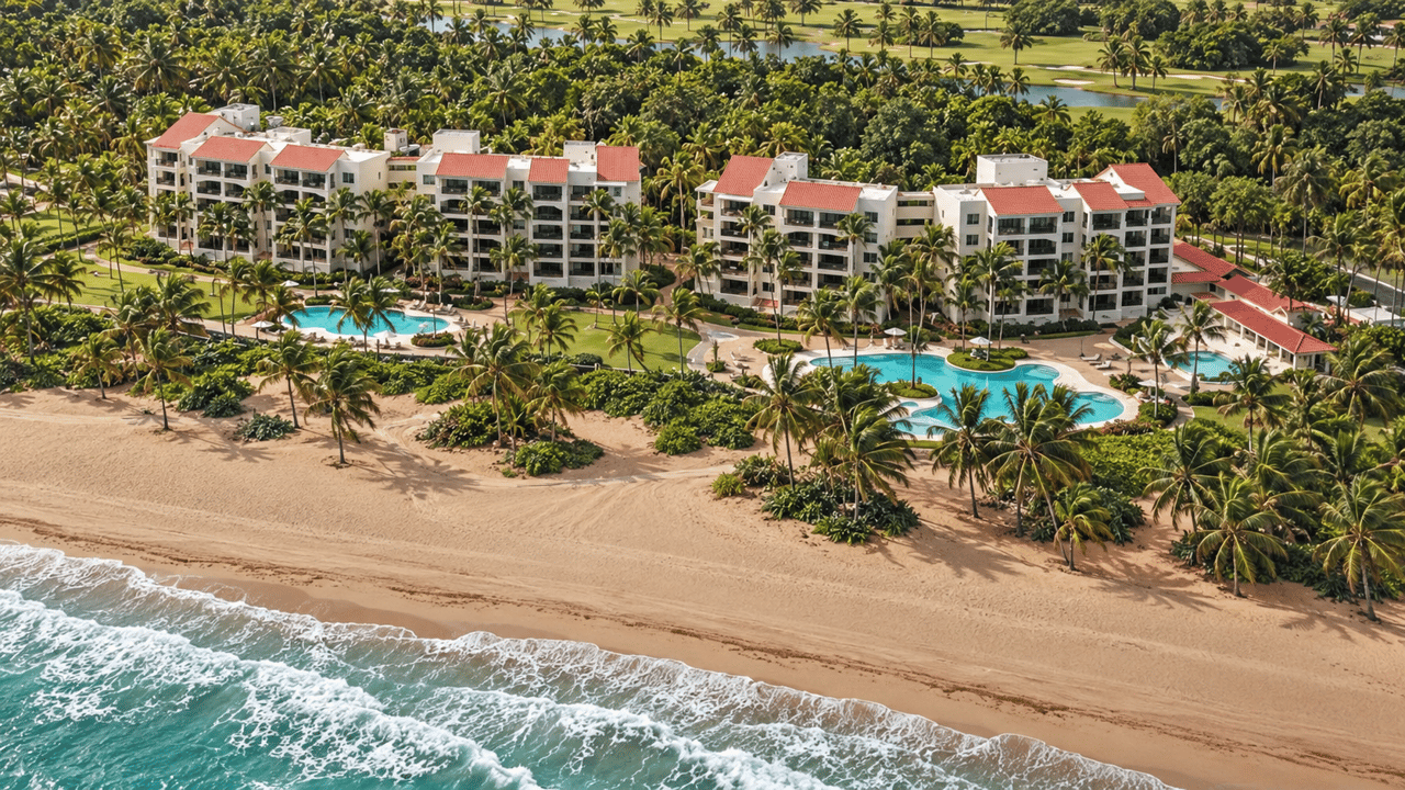 Ocean Villas beachfront condos with red tile roofs, pools, palms, and sandy shoreline