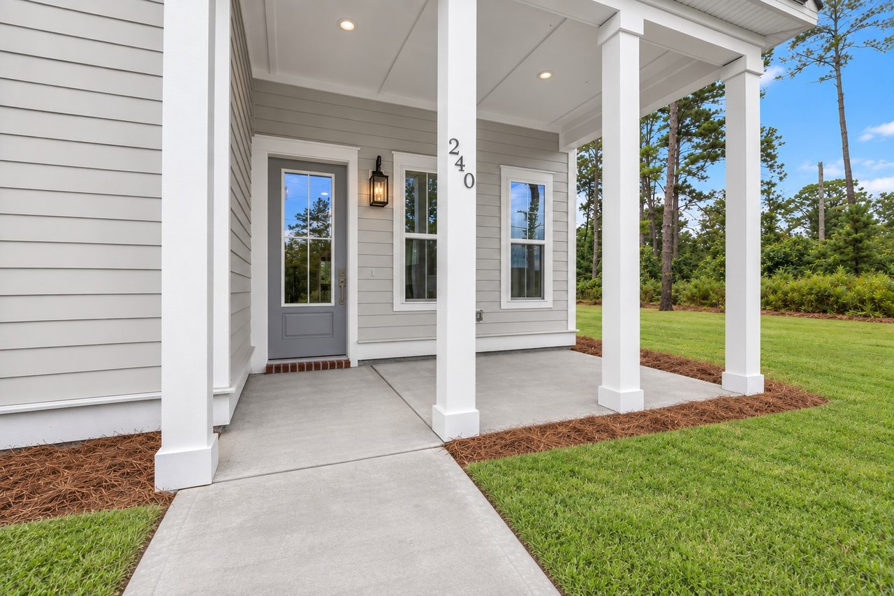 Light gray home with a covered white-columned porch, gray door, and concrete walkway.