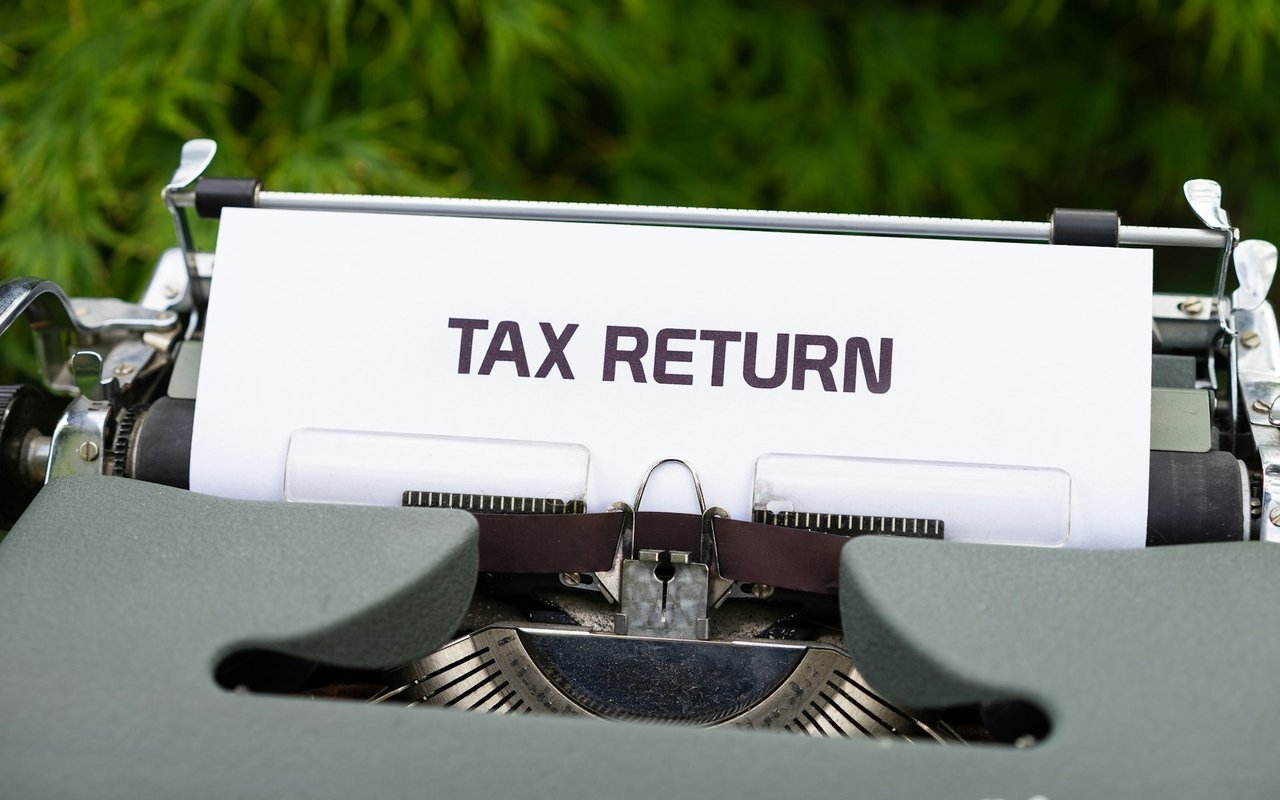 A sheet labeled “TAX RETURN” sits in a vintage typewriter.