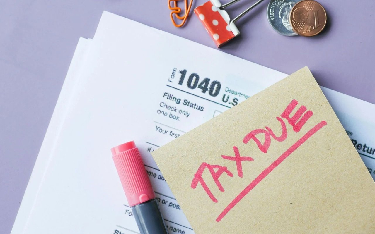 Tax return form with a handwritten “Tax Due” note, pink marker, and coins.