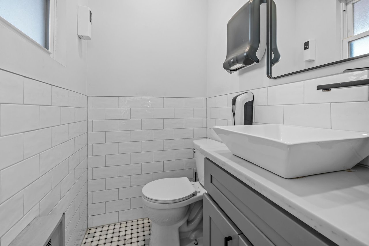 Bathroom with white subway tile, mosaic floor, and vessel sink on a gray vanity.