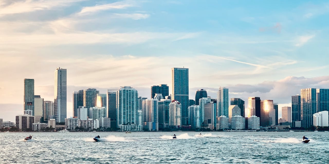 Miami skyline across the bay, with high-rises and jet skis on the water.