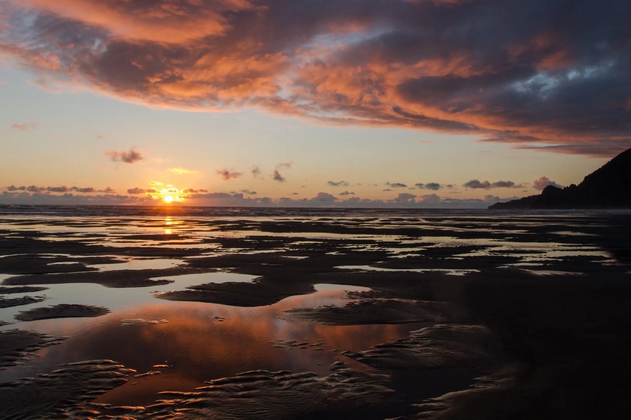 pools of water on the manzanita Oregon beach with the sun setting a reflection in the pools