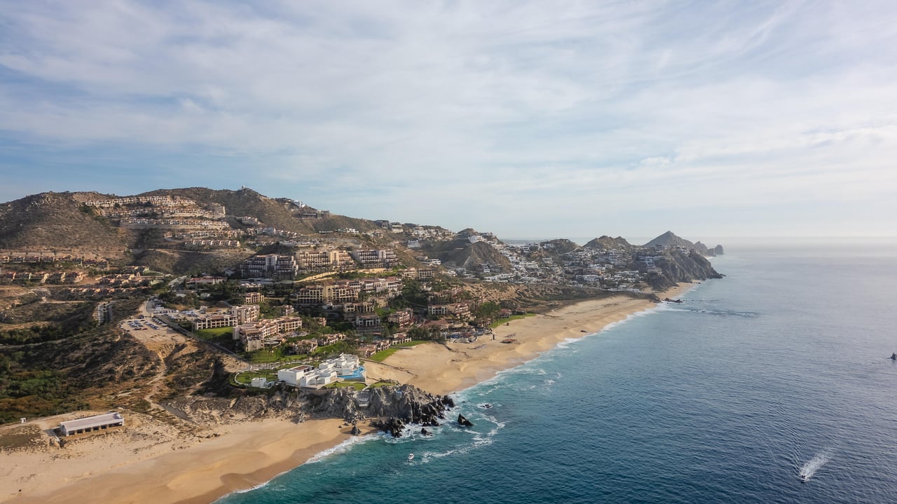 Aerial view of Quivira’s Pacific beaches at sunset with Cabo San Lucas in the distance