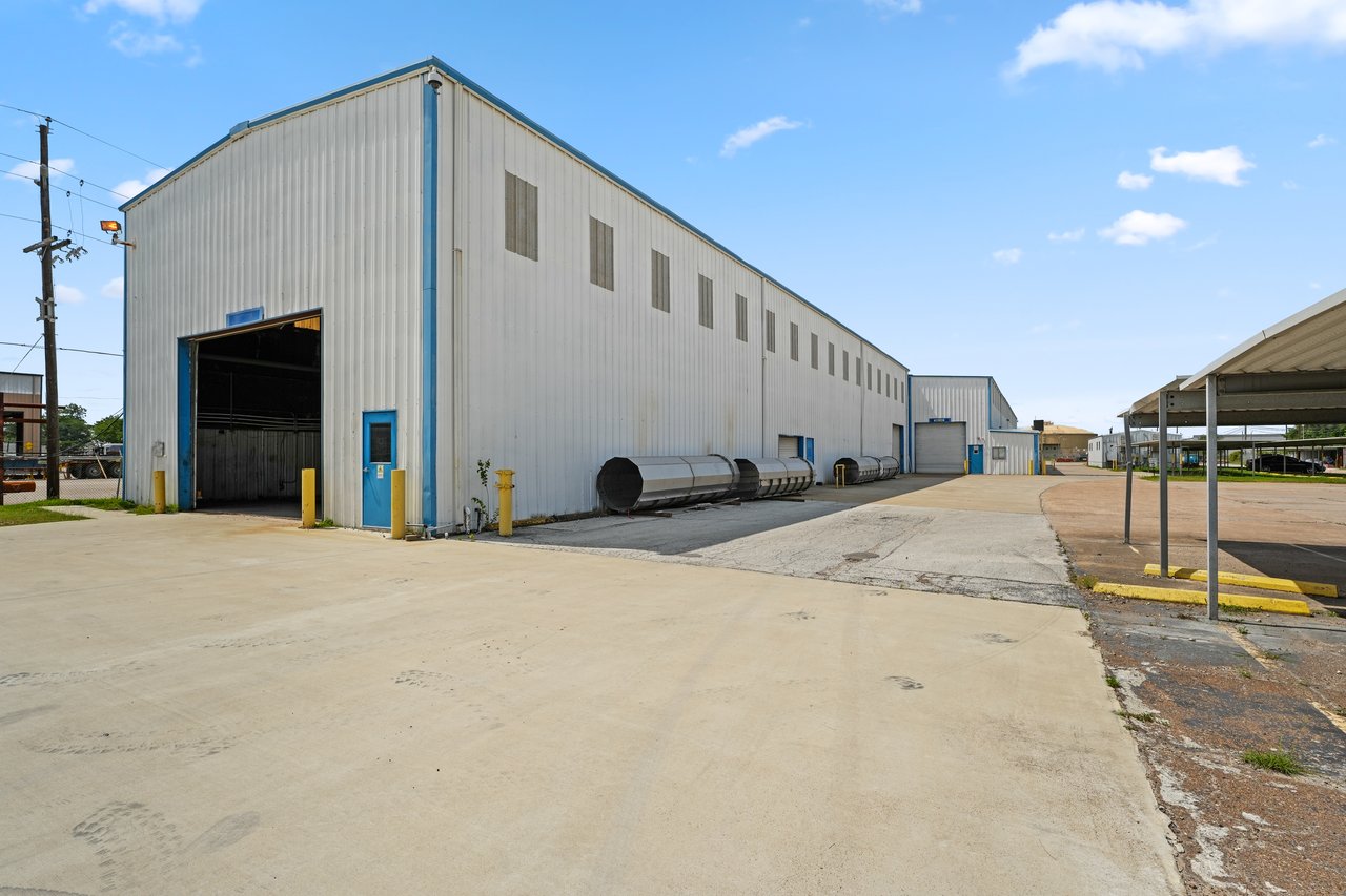 Industrial warehouse with blue-trimmed loading bays and a broad paved yard.