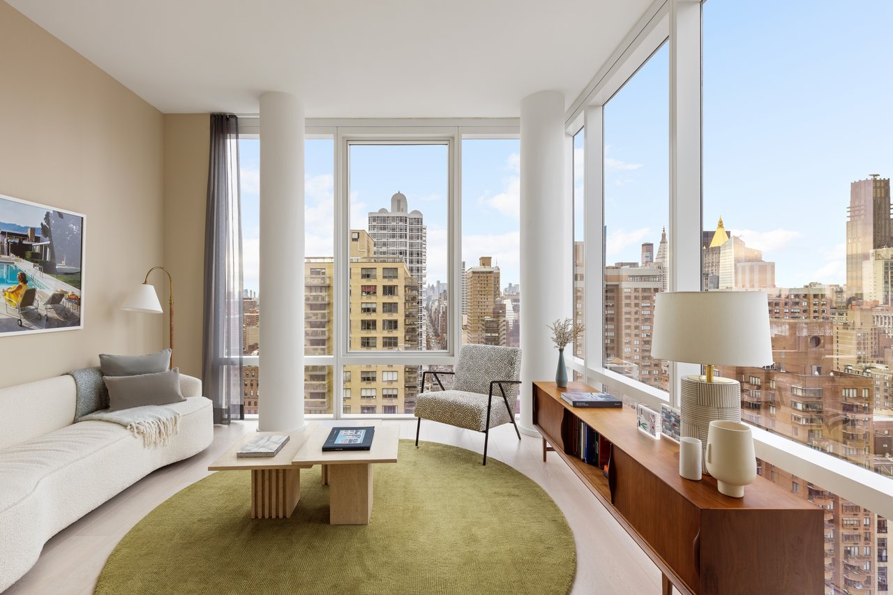 Furnished living room with floor-to-ceiling windows overlooking the city skyline.