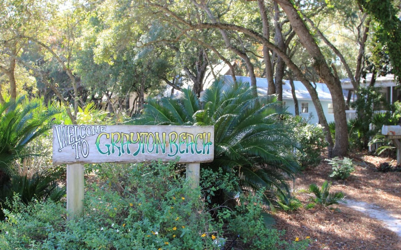 Welcome to Grayton Beach sign surrounded by trees and lush greenery.
