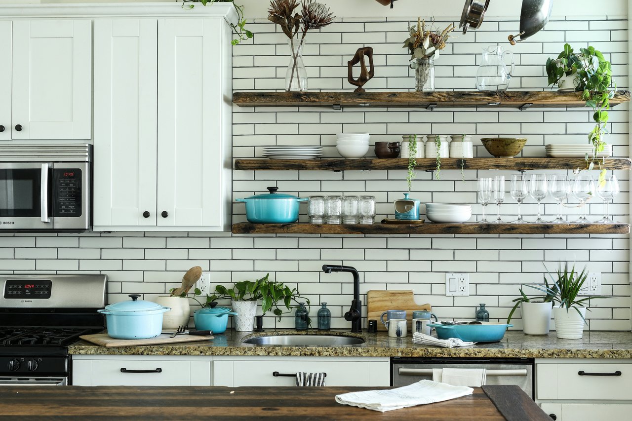 Kitchen with white shaker cabinets, subway tile, reclaimed wood open shelves, and turquoise cast-iron cookware