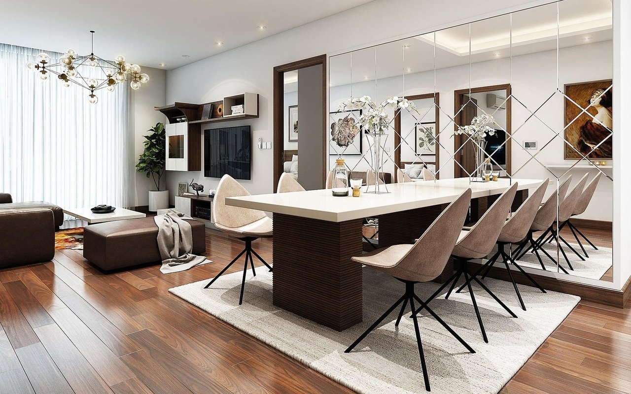 Open-plan dining room with a long white table, mirrored wall, and geometric chandelier.