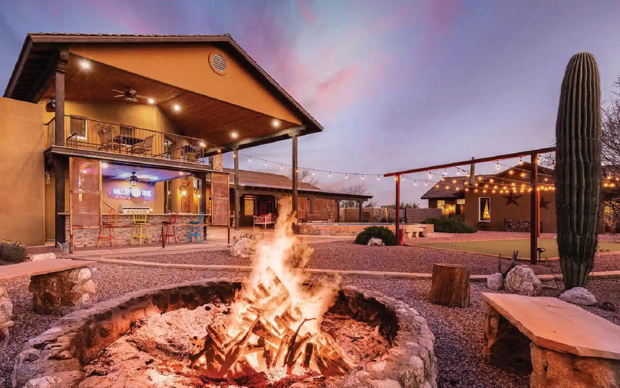 Ranch-style home in Tanque Verde, Tucson, featuring an outdoor living area with a fire pit, patio bar, and desert landscape.
