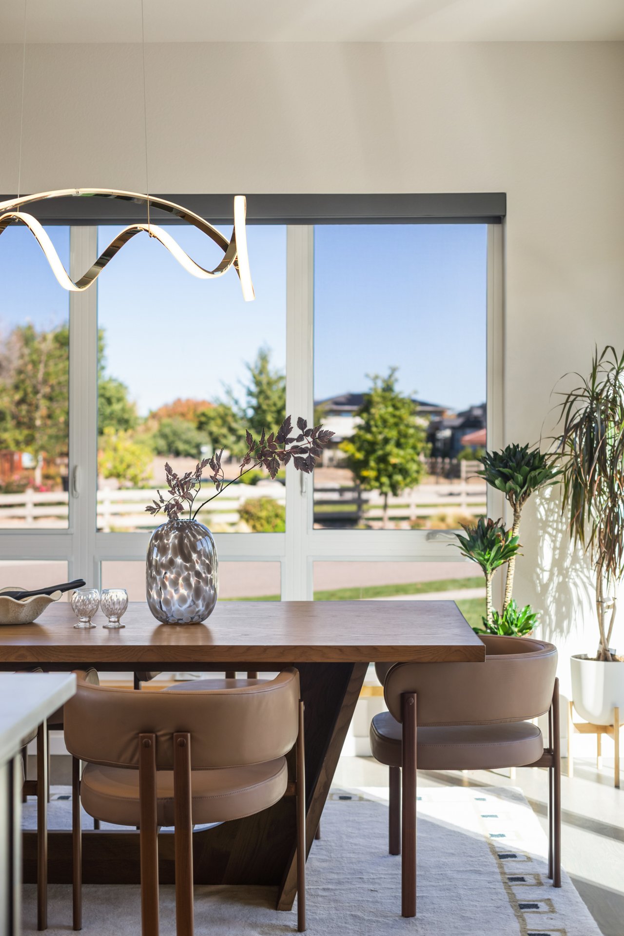 Close-up of a vase on the dining table with windows looking out to the street and neighboring homes