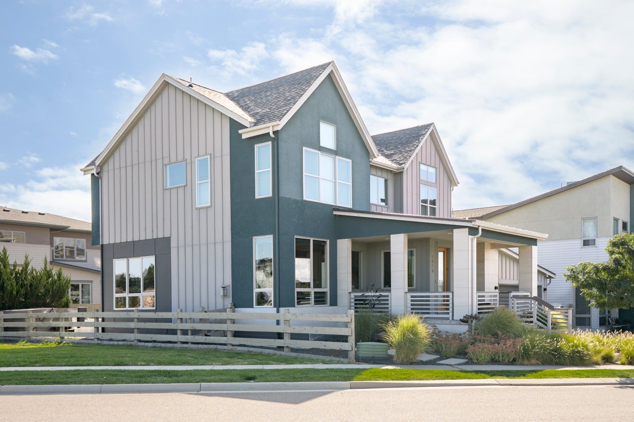 Angled street view of the home with a wood rail fence and a front porch with white railings