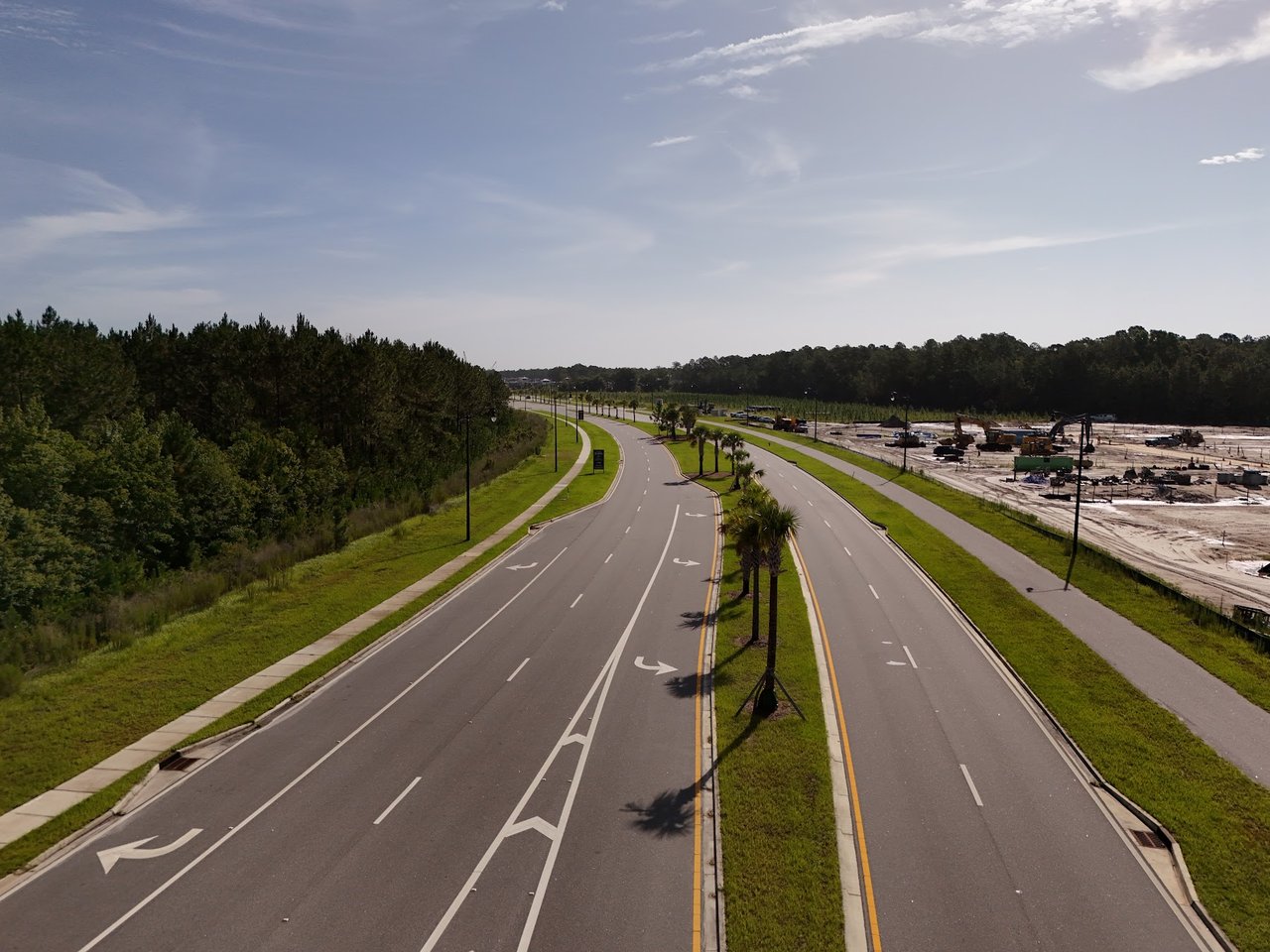 Divided Silver Meadows road with a palm-lined median and nearby construction site.