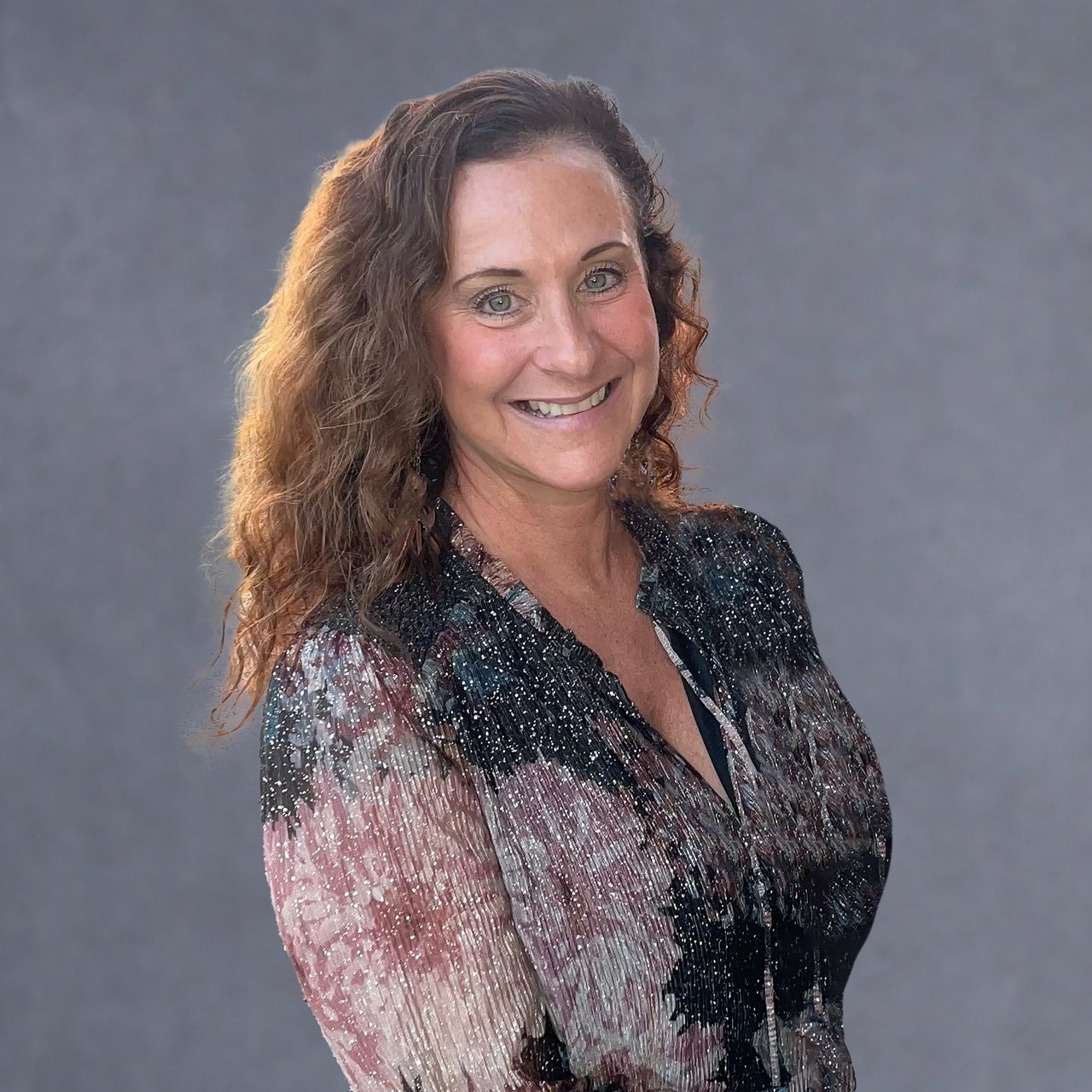 Toni Enos smiling in a patterned blouse.