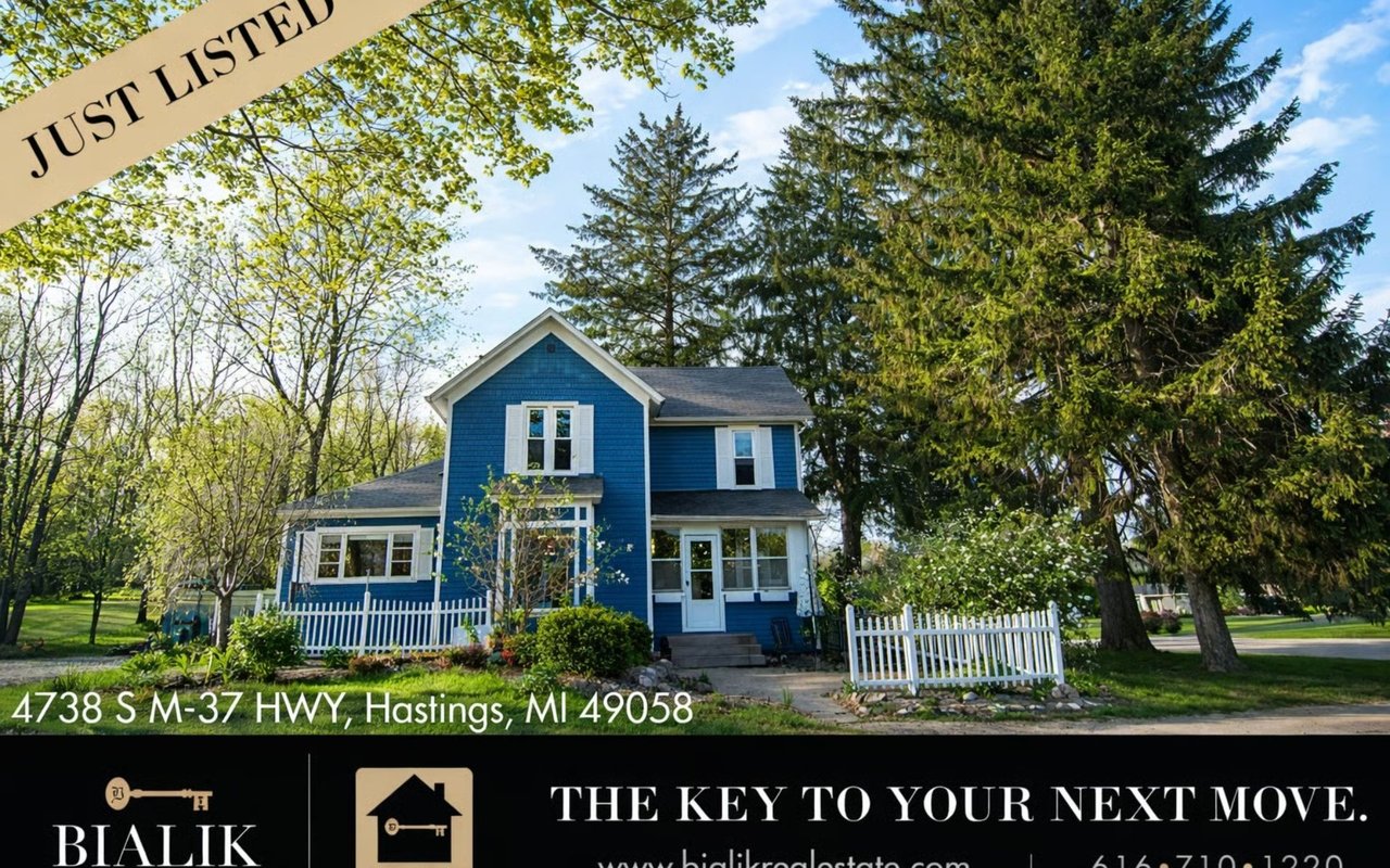 Blue two-story home with white trim, a picket fence, and mature trees.