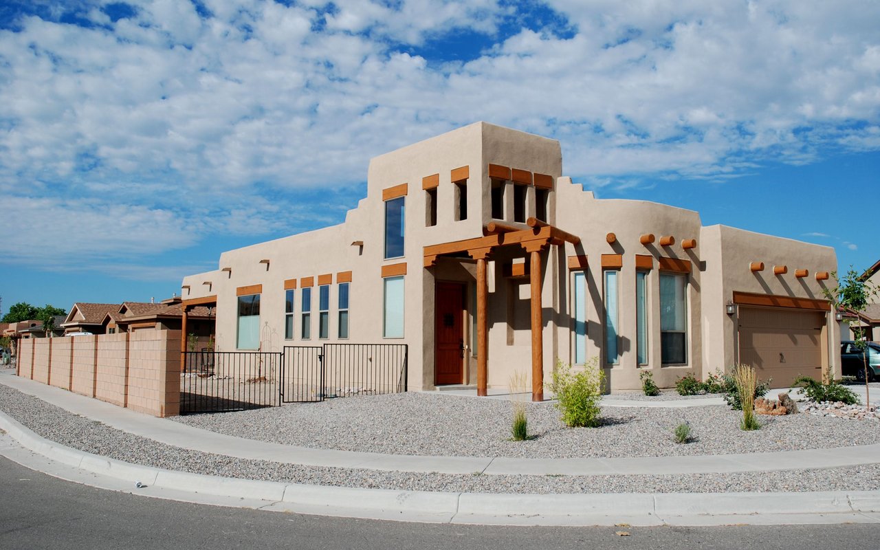 Southwestern-style stucco home with timber porch posts, a garage, and gravel landscaping.