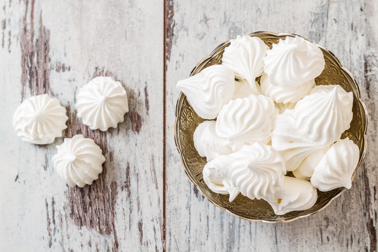 Golden-white meringue cookies piled high on a plate.
