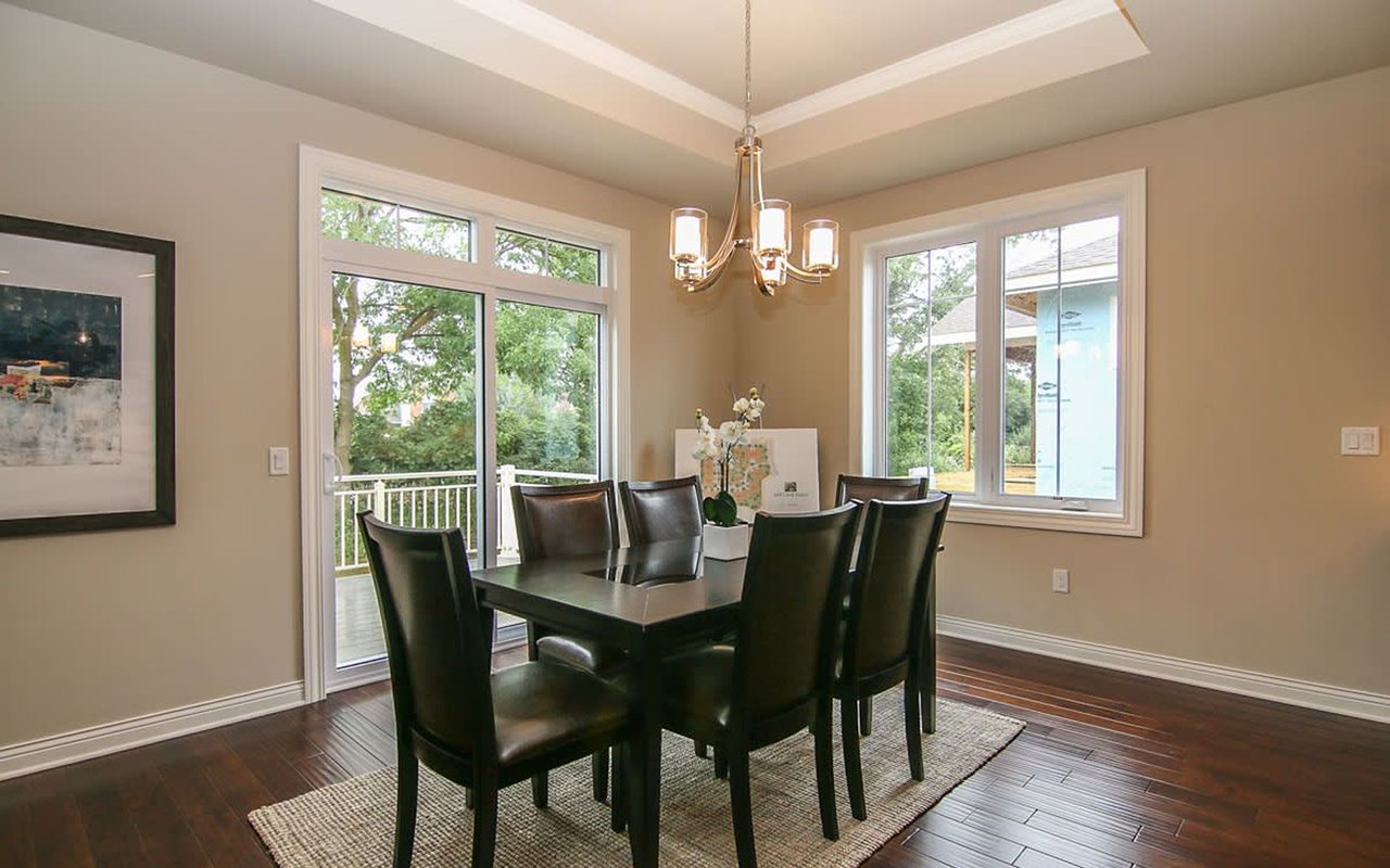 Dining room with a dark wood table, leather chairs, large windows, and a glass door to the deck.
