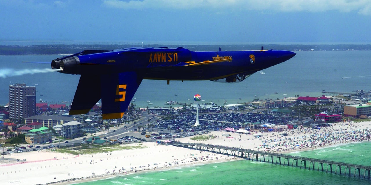 A blue angels fighter jet upside down at an aerial show in Pensacola beach florida