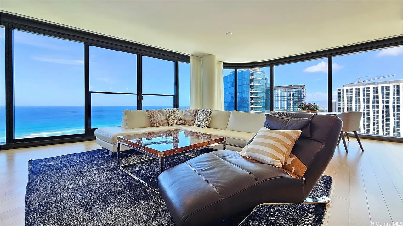 Furnished condo living room with a cream sectional and panoramic ocean and city views.